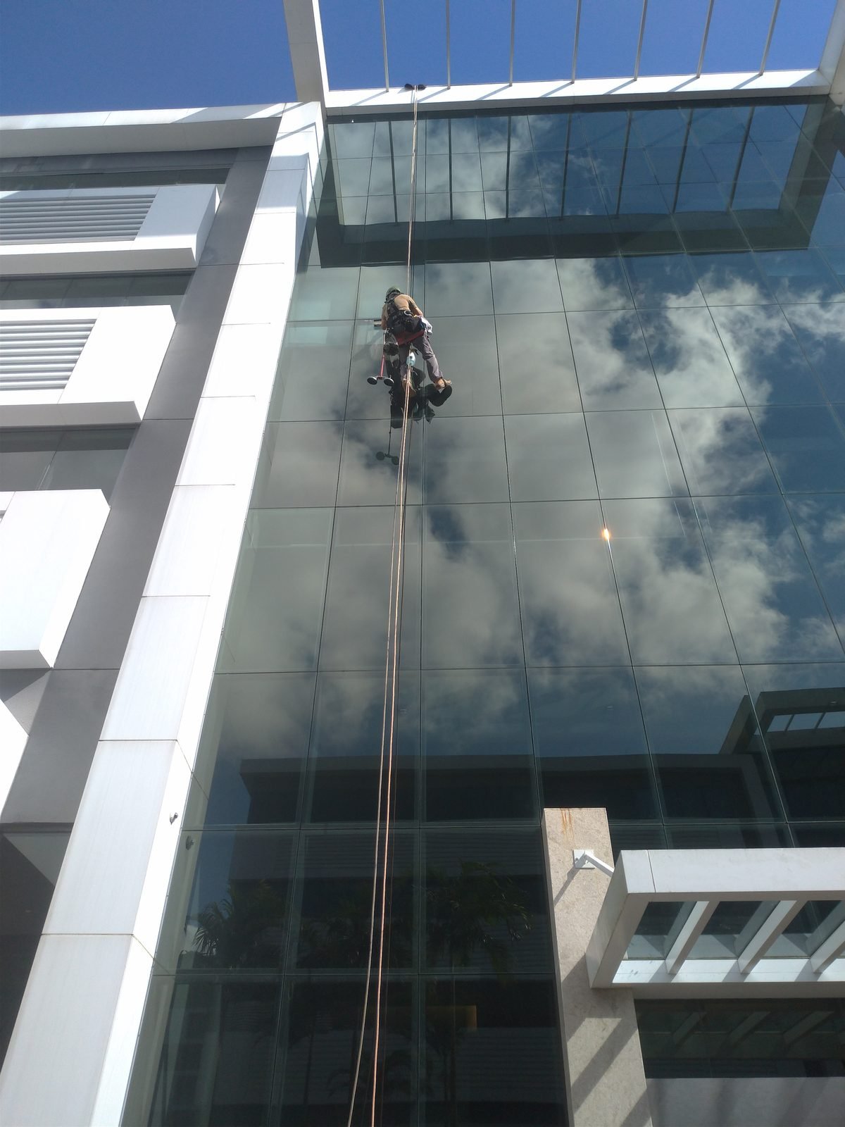 Profissional trabalhando em fachada de vidro de edifício corporativo
